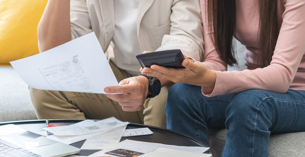 Calculatrice financière posée sur tableaux d'amortissement de crédit immobilier imprimés en français avec annotations manuscrites de calculs de coûts