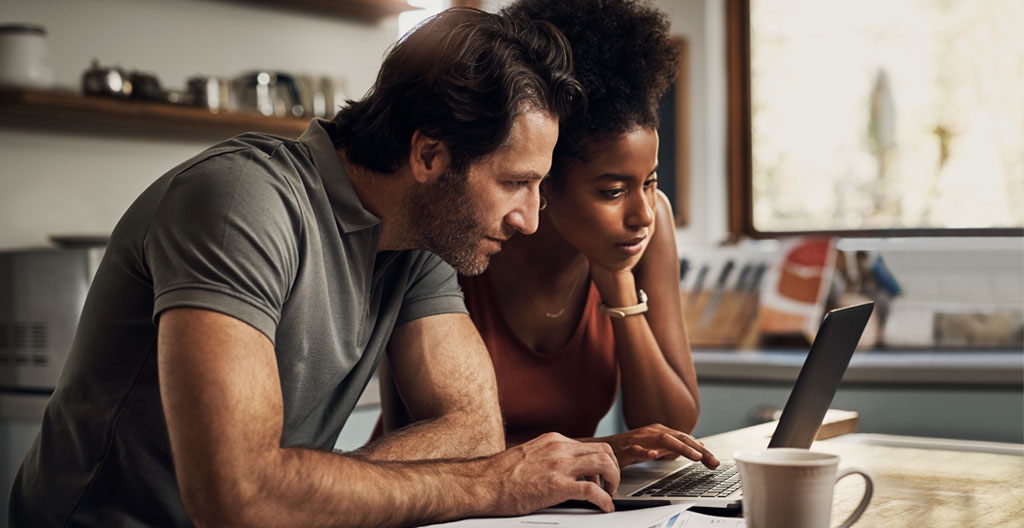 Personne utilisant un simulateur de crédit immobilier en ligne sur ordinateur portable dans un intérieur domestique français contemporain, interface en français affichée à l'écran